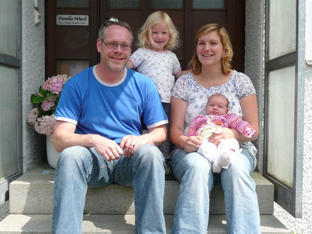 Eine Familie sitzt vor einer Haustür.